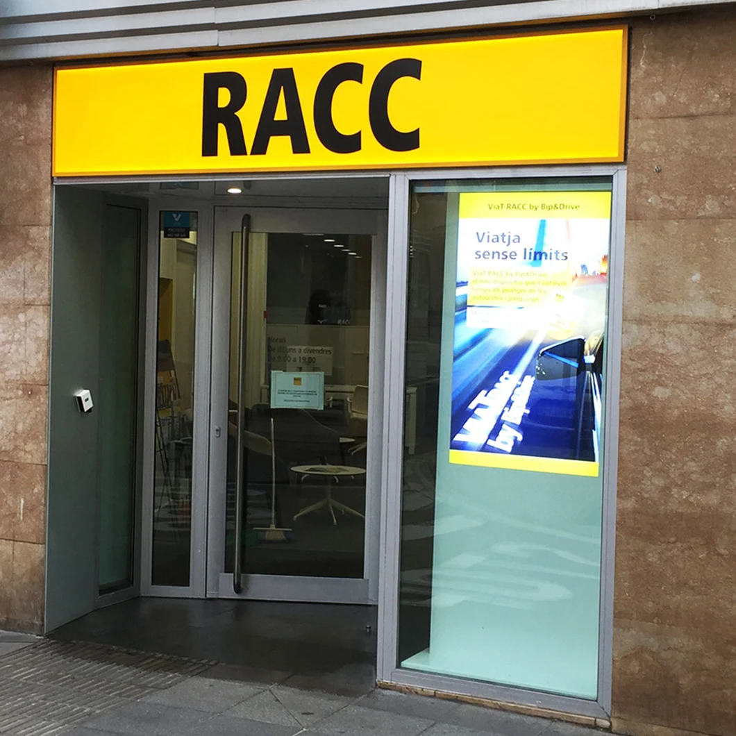 RACC store entrance with a vertical digital screen in the shop window displaying a travel campaign