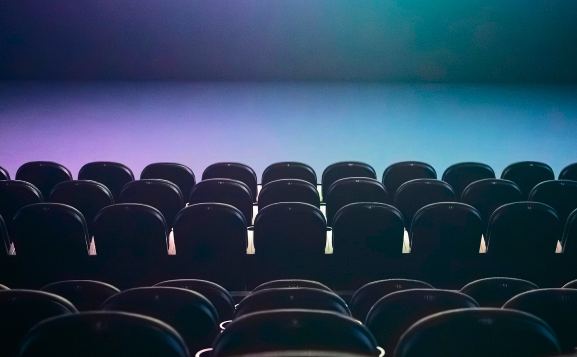 Rows of empty cinema seats facing a softly lit purple and blue screen