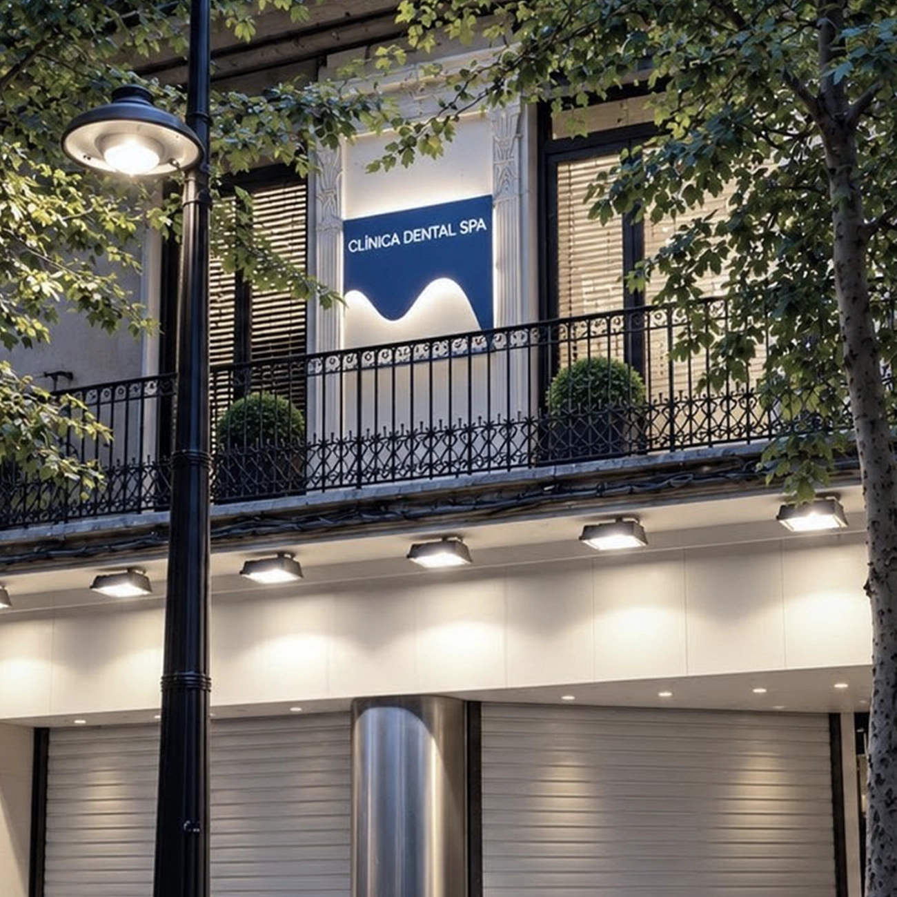 Clínica Dental SPA building façade at night, with illuminated signage on the first-floor balcony and shuttered street-level storefronts.